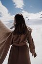 Woman Standing on Snowy Plains with Scarf Fluttering on Wind Behind Her