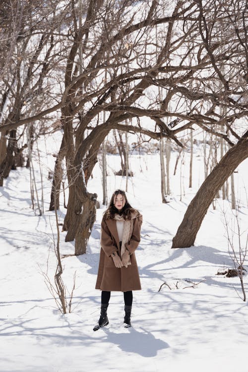 Woman in a Brown Coat Standing Under Bare Trees