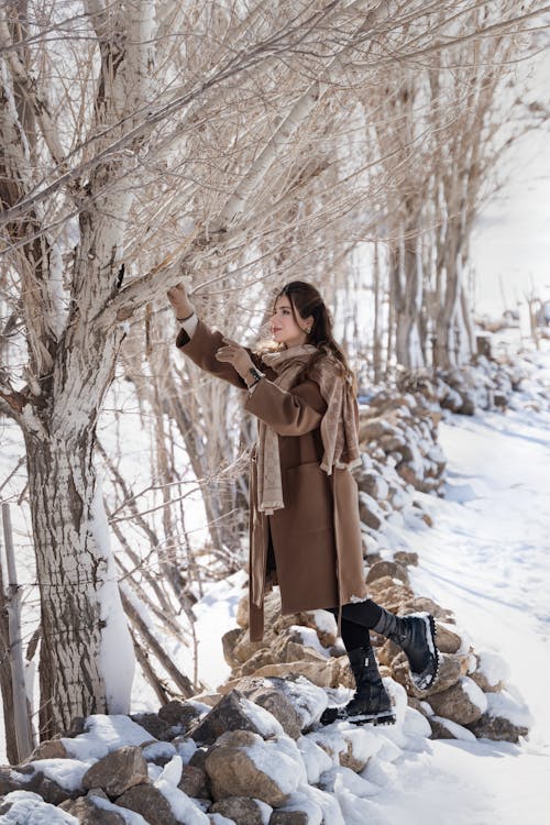 Woman in Winter Clothes Standing Near Bare Trees