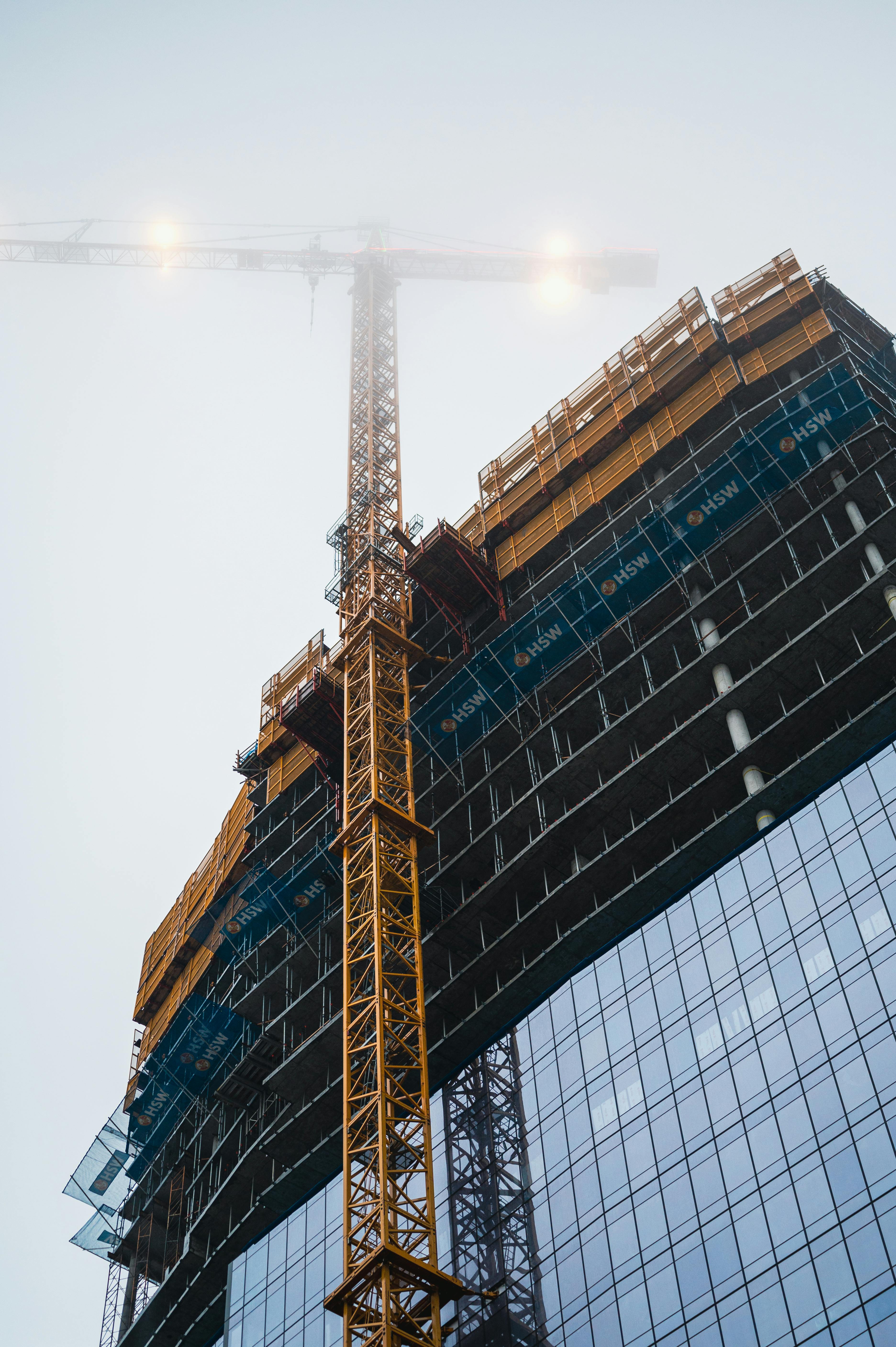 view of office building facade and construction crane with top in fog