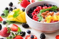 这只充满活力的碗里装满了新鲜的浆果、芒果、杏仁和香草，非常适合作为健康的零食或早餐