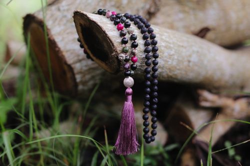 Free Close-up of a purple beaded tassel necklace draped over a log outdoors. Stock Photo