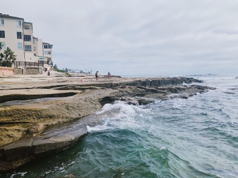A scenic view of waves crashing on a rocky shoreline near a coastal resort.