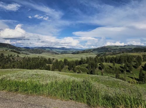 Free Breathtaking view of green countryside with hills and a vibrant blue sky. Stock Photo