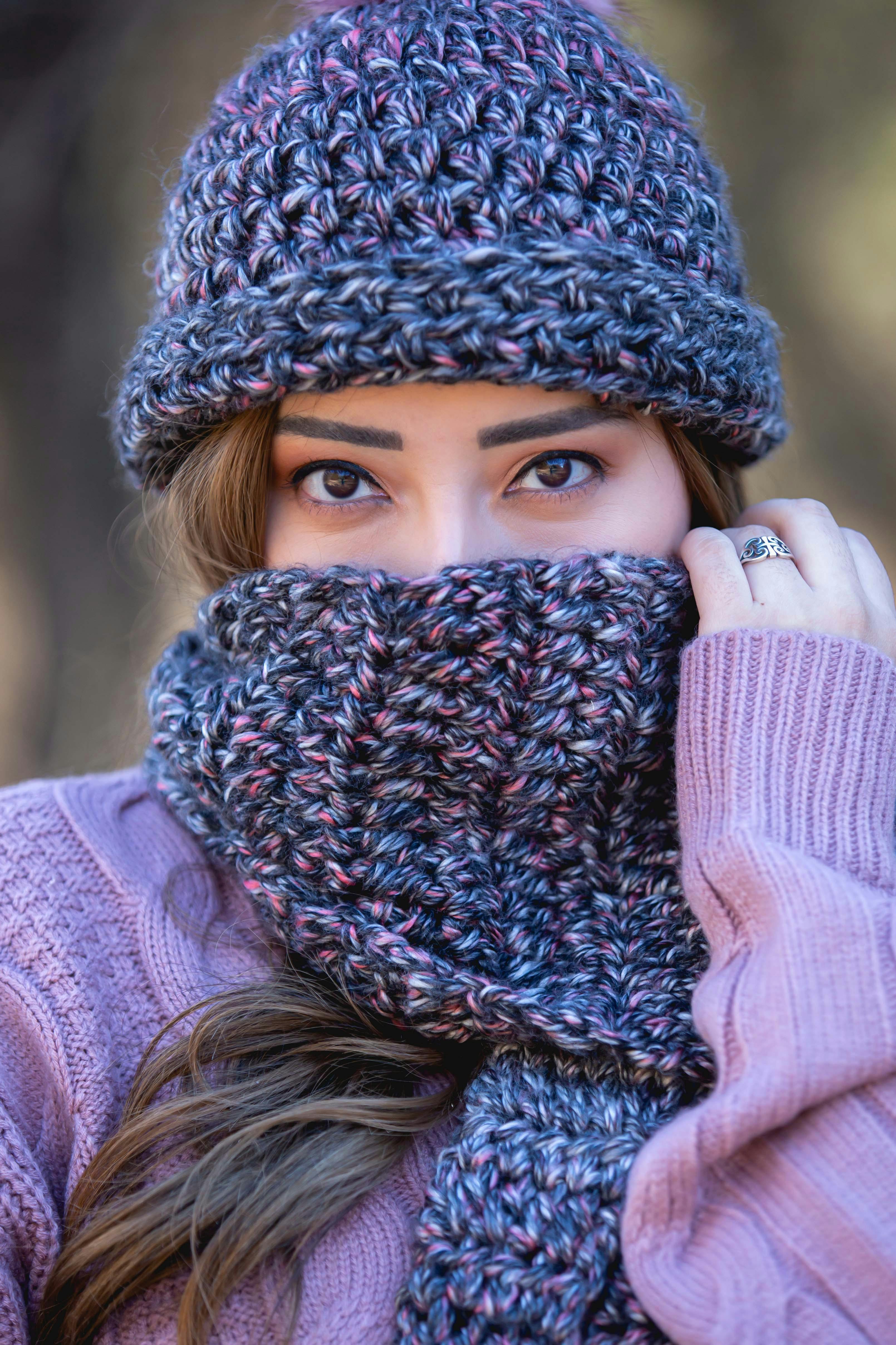 A woman warmly dressed in a knitted beanie and scarf, showcasing winter fashion style.