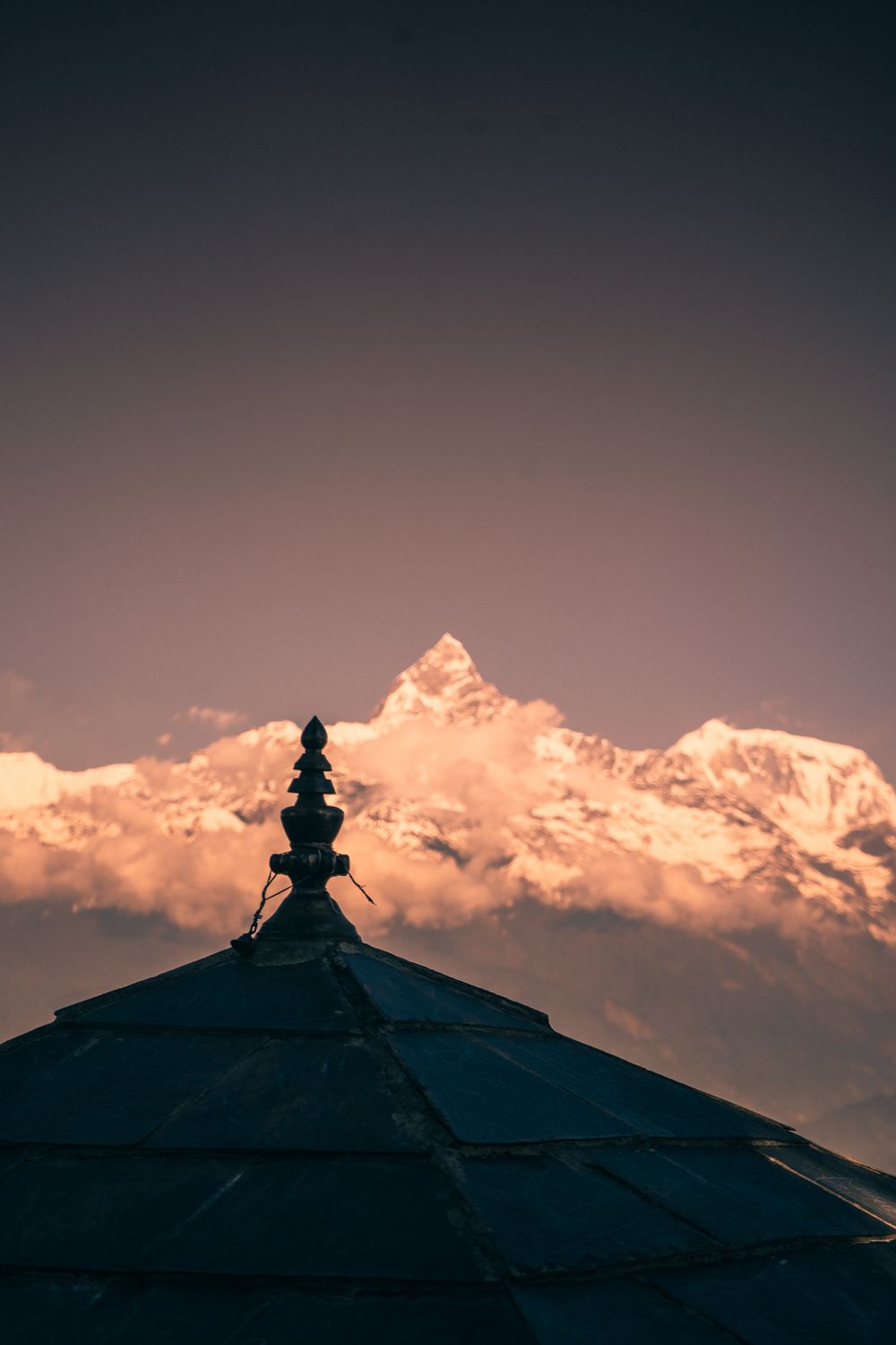 O topo de um templo diante dos picos nevados do Himalaia, em Pokhara