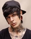 Trans Person with Cap on Head and Tattoos on Neck and Cleavage