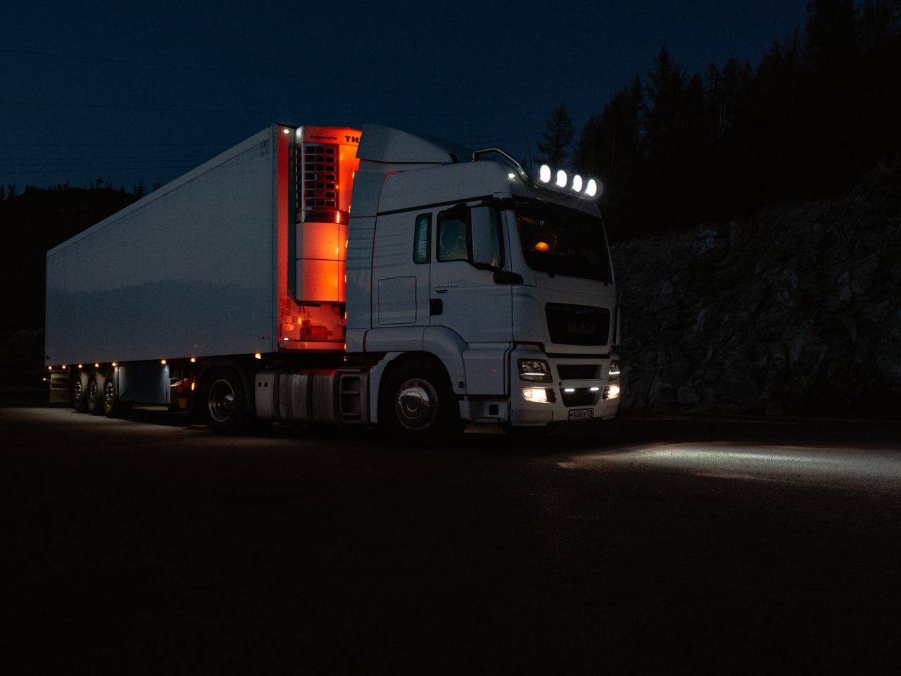 A modern lorry lit up at night on a mountain road