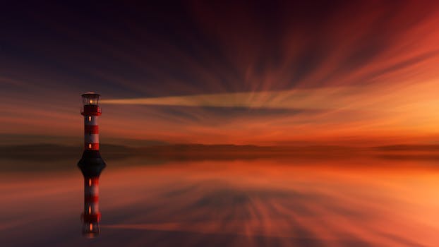 A stunning lighthouse silhouette during sunset reflecting in calm ocean waters.