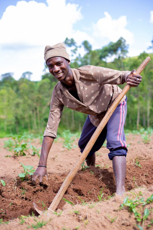 A Woman Holding a Hoe on Dirt Ground
