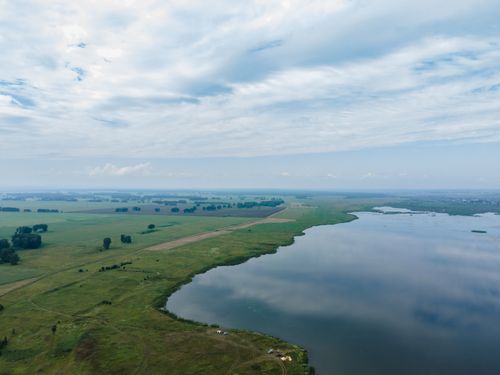 Free Drone shot of a vast lake and rural landscape in Kemerovo, Russia, showcasing serene nature. Stock Photo