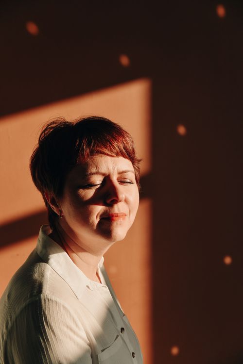 Free Close-up of a smiling woman with short red hair, basking in warm sunlight. Stock Photo