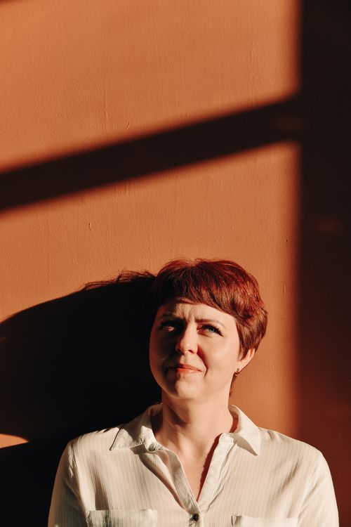 Free Portrait of a redhead woman with short hair in sunlight and shadow, expressing serenity. Stock Photo