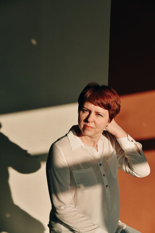Free Woman with short hair poses in sunlight indoors wearing white shirt. Stock Photo