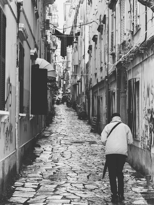 Free Grayscale Photo of a Person Walking in a Alley Stock Photo