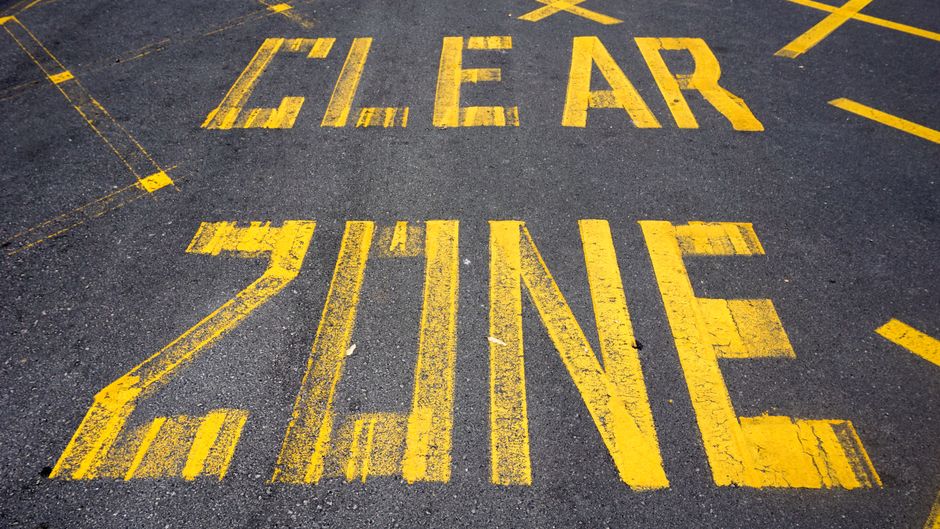 Close-up view of 'Clear Zone' road markings painted in yellow on asphalt in New Zealand.