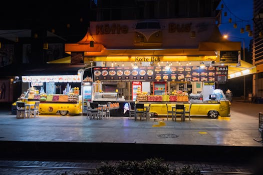 A vibrant street food stall serving köfte and fruit at night.