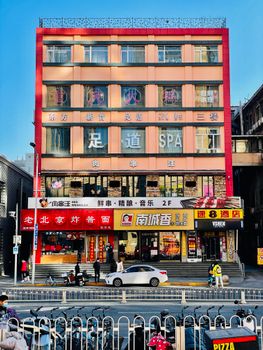 Colorful street scene showcasing shops, bicycles, and pedestrians in front of a multi-story building.