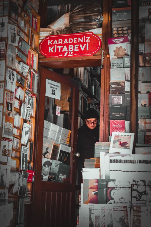 Free A customer browses books inside a cozy, packed bookstore, offering a vintage feel. Stock Photo