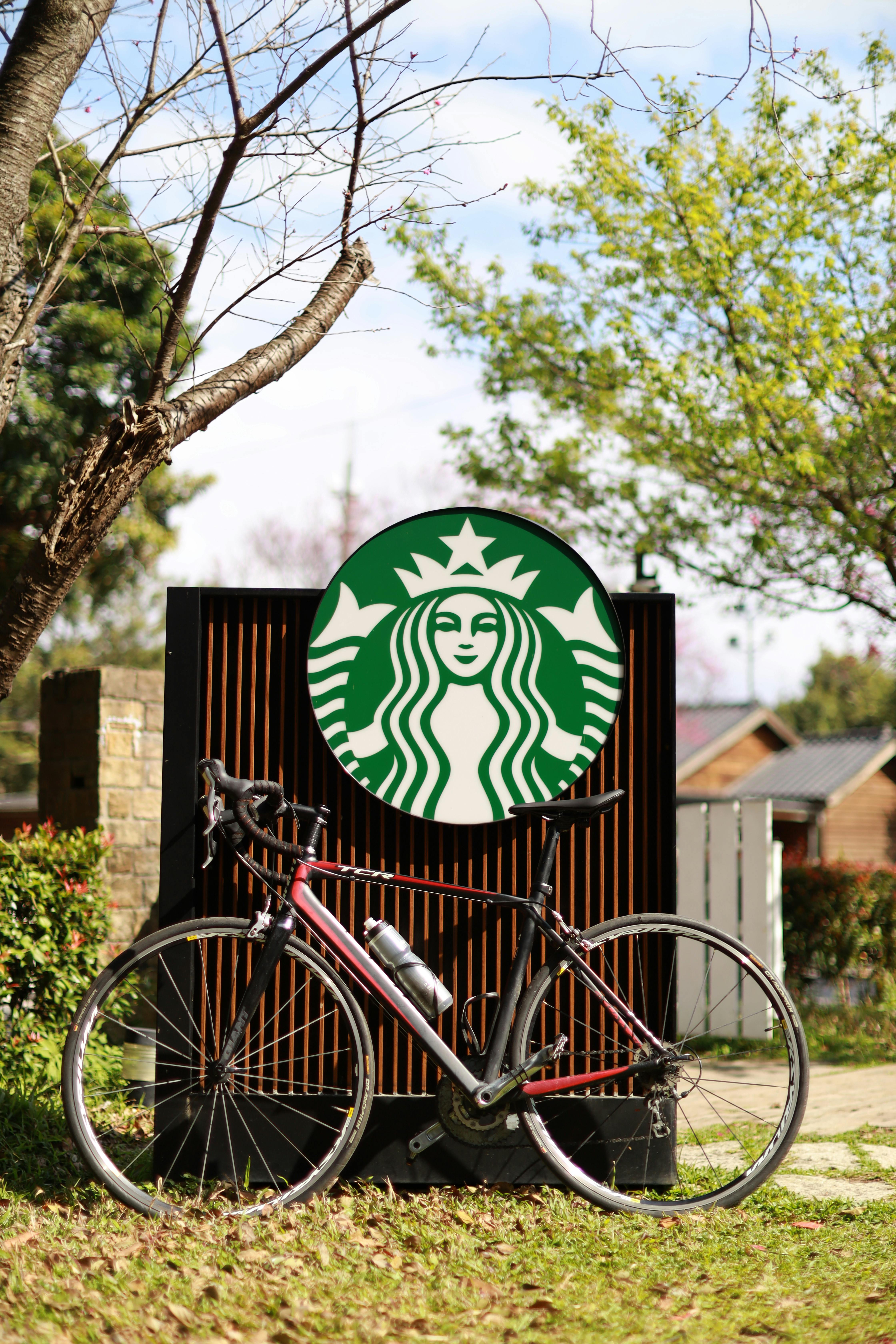 A bicycle rests against a Starbucks sign in a sunny outdoor setting in Taipei City, Taiwan.
