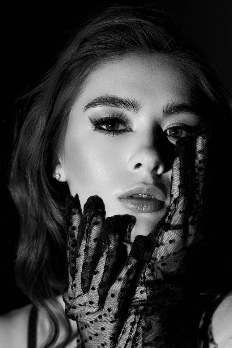 Black And White Portrait Of Woman Touching Face With Hands In Transparent Gloves
