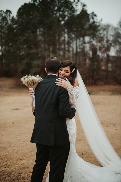 Bride and groom embracing in a field during their wedding.
