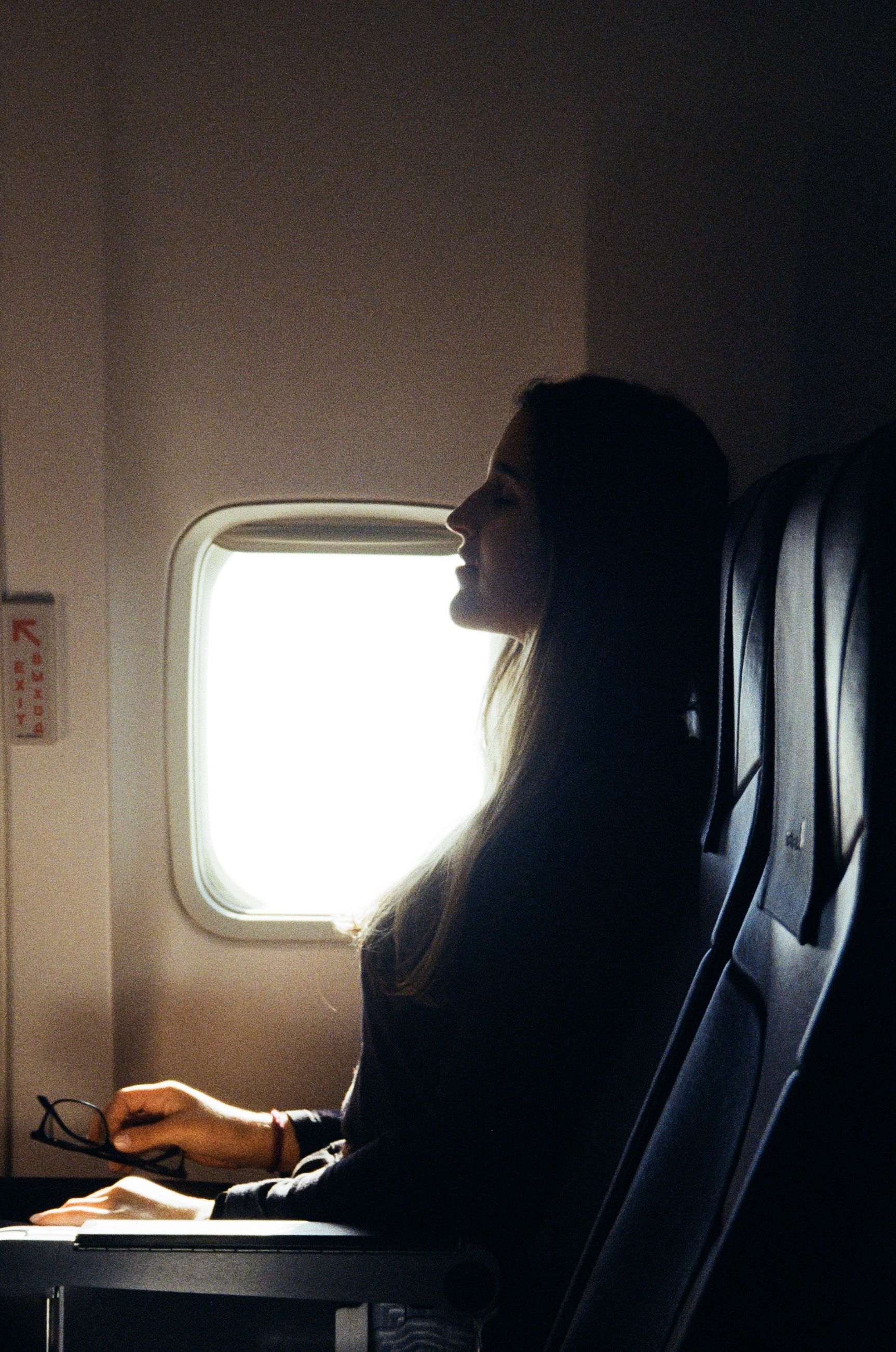 Woman relaxing on an airplane by the window during a daytime long-haul flight