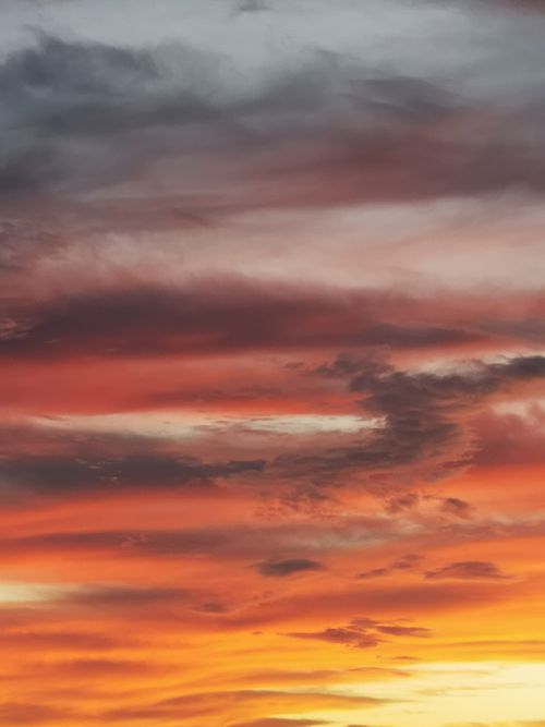 Free A stunning sunset sky with dramatic clouds and vibrant orange hues, perfect for nature and travel themes. Stock Photo