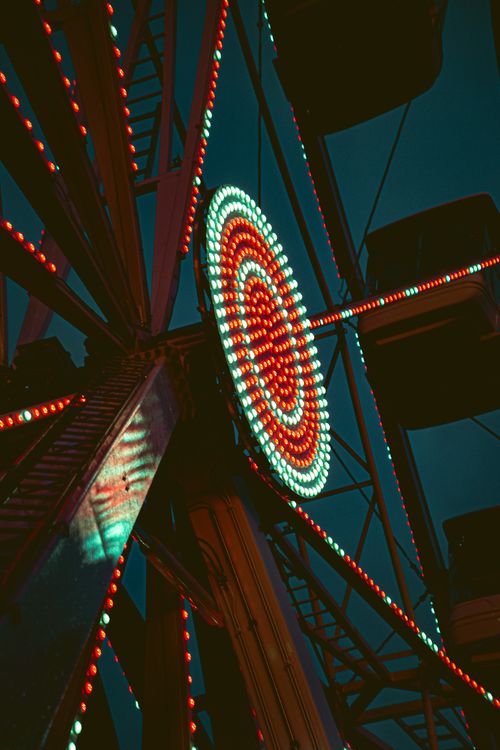 Free Low-angle view of a vibrant, illuminated Ferris wheel at night creating a dramatic visual spectacle. Stock Photo