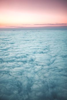 Stunning aerial view of dense clouds during a colorful dawn sky, showcasing nature's beauty.