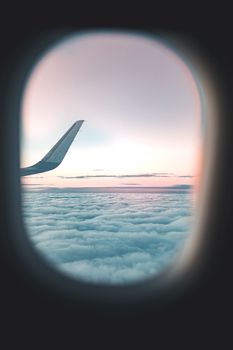 View from airplane window showing wing and clouds at sunset.