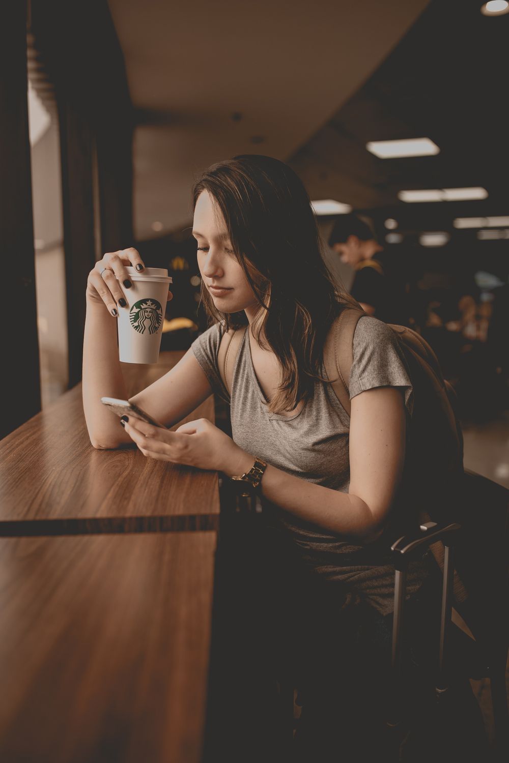 Close-Up Shot of a Woman Holding a Cup of Coffee while Using a ...