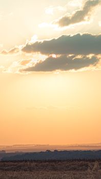 Beautiful sunset sky with clouds over a tranquil open field landscape.