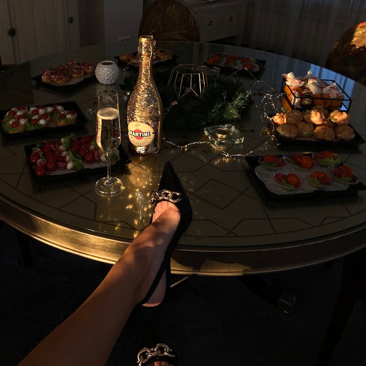 Woman Leaning Leg On Table With Wine And Elegant Snacks 