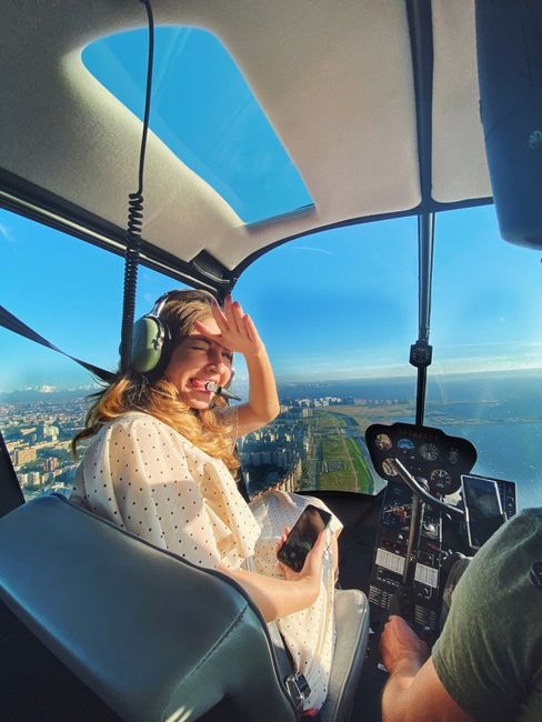 A woman enjoys a scenic helicopter ride, capturing the moment on her smartphone