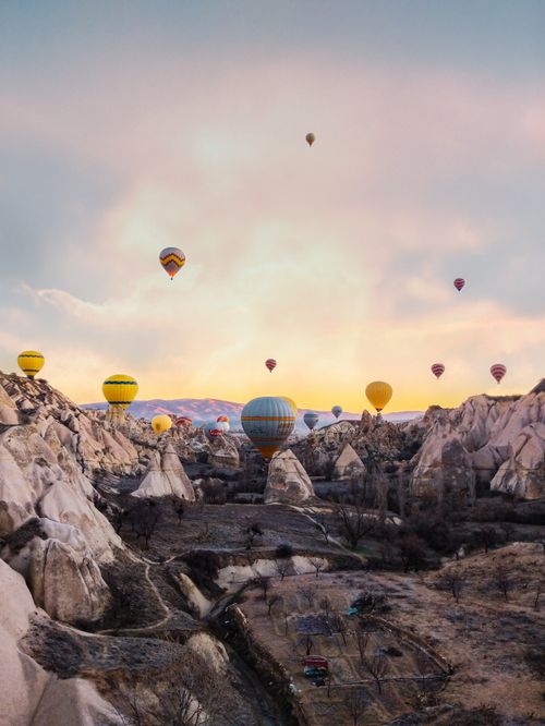 Free Colorful hot air balloons floating over Cappadocia's stunning rock formations at sunrise. Stock Photo
