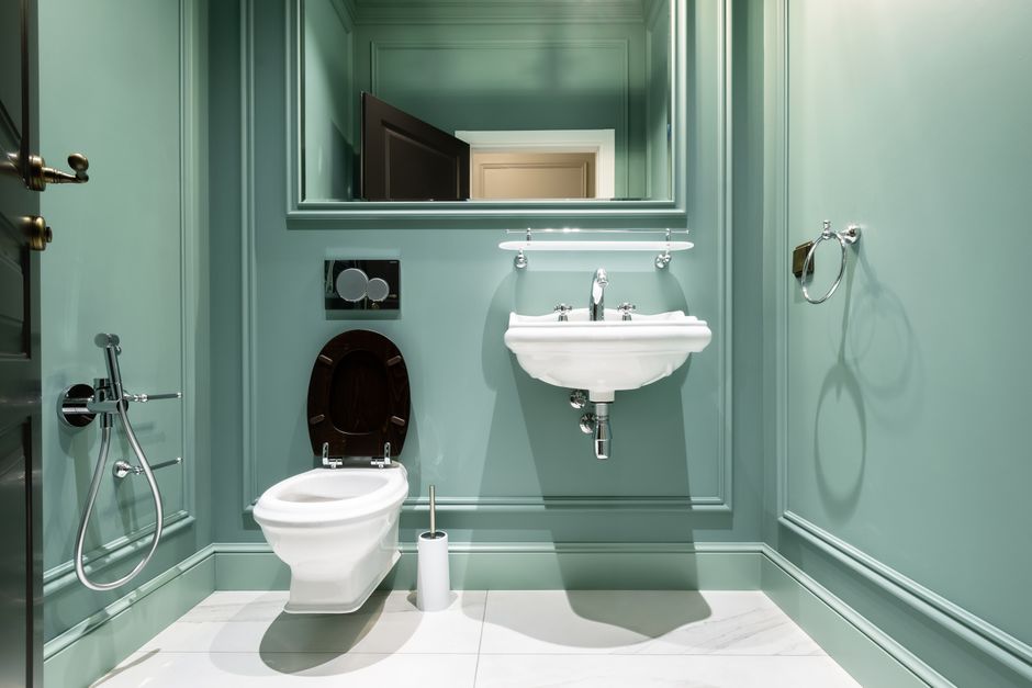 Kleines Gäste-WC mit wandhängendem WC, schmalem Eckwaschbecken und hellem Fliesenspiegel