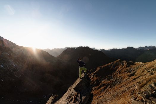 一名徒步旅行者站在山顶，欣赏着广阔山脉上令人惊叹的日出