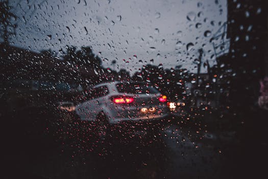 Moody street scene through a rain-covered window in Palakkad, India, capturing evening traffic.