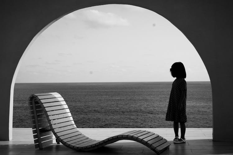 Silhouette Of Little Girl Standing By Chaise Longue 