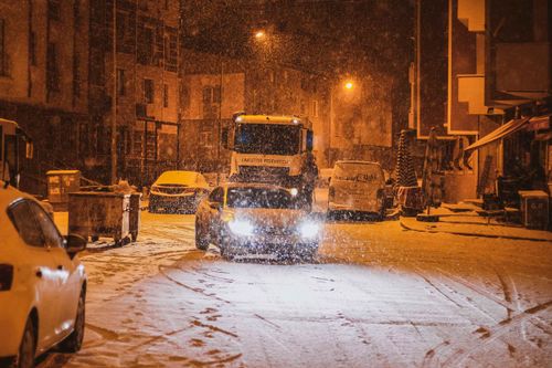 Free A serene winter night scene of snow-covered street with parked vehicles. Stock Photo