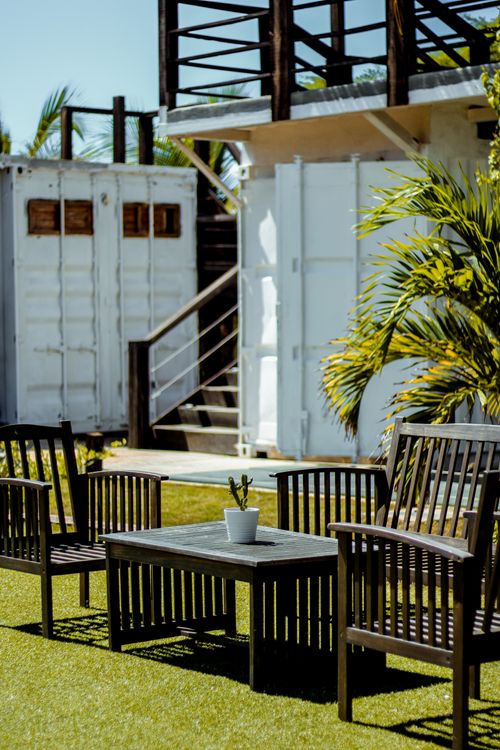 Free Cozy garden seating with wooden chairs and a table under tropical sun, perfect for relaxation. Stock Photo