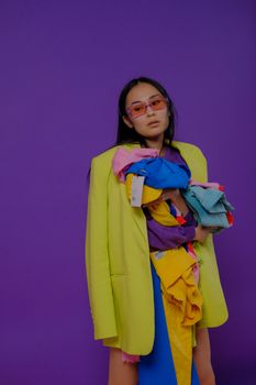 Stylish woman in a bright outfit poses against a vibrant purple backdrop.