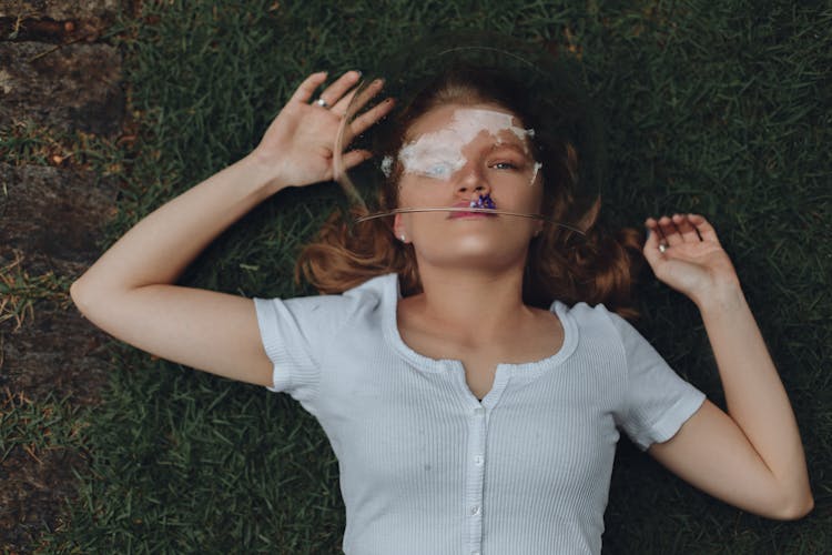 Woman Lying On Grass Wearing Glass Bowl On Head