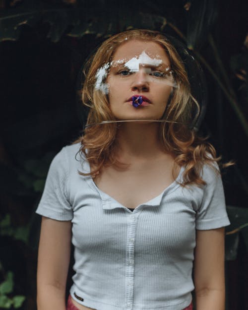 Portrait of Woman Wearing Glass Bowl on Head Holding Flower in Mouth