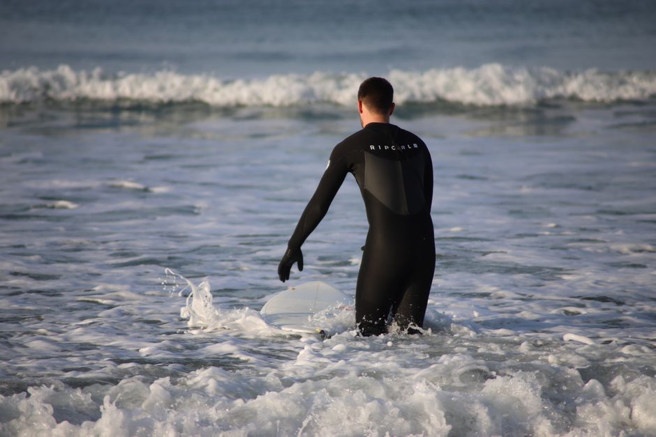Surfer in a wetsuit prepares to ride waves on a beach in Pays de la Loire, France.
