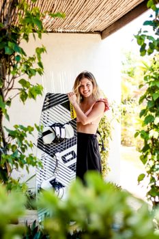 A smiling woman holds a kiteboard in a lush, sunny outdoor setting, radiating joy and adventure.