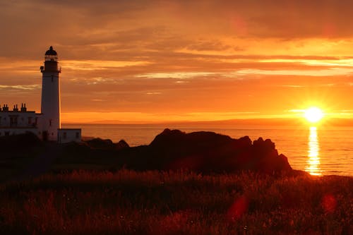 Photo of a Lighthouse Near a Body of Water During Sunset