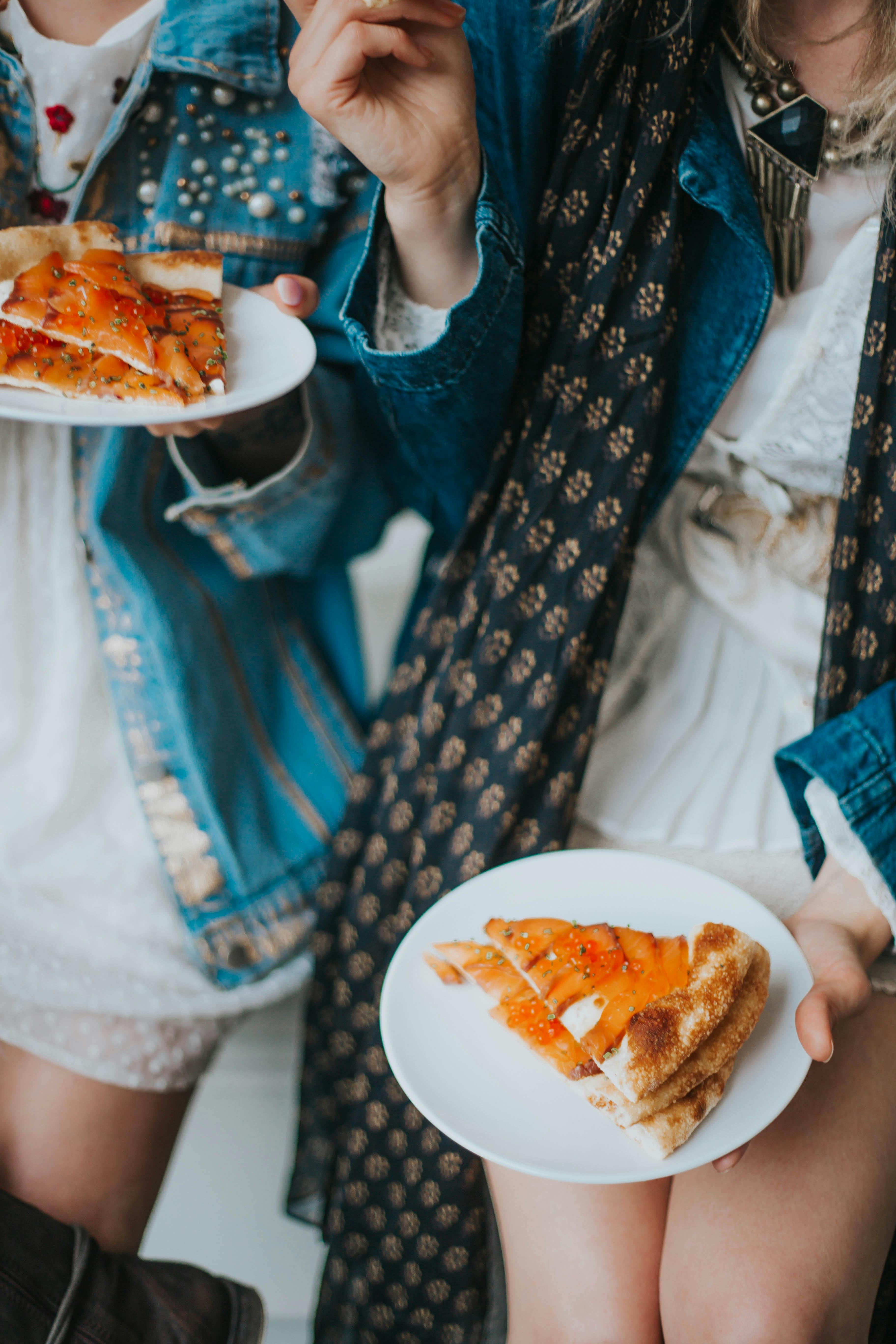 Two teenagers having a casual pizza party indoors, capturing a fun and relaxed moment.