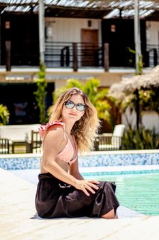 Stylish woman in sunglasses lounging by the poolside in sunny Adicora, Venezuela.